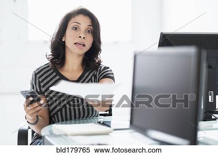 Stock Photography - Mixed race businesswoman working at desk. Fotosearch