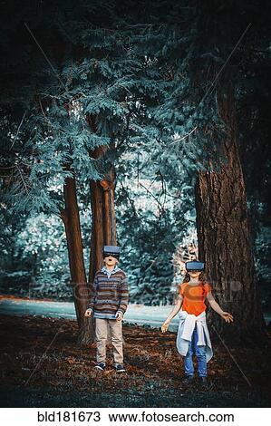 Stock Image - Mixed race children using virtual reality goggles outdoors. Fotosearch