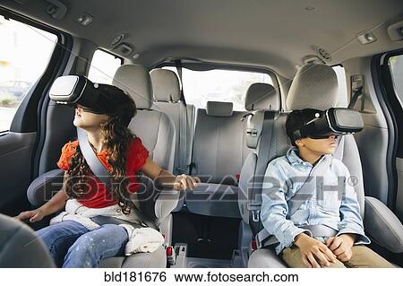 Stock Photograph - Mixed race children using virtual reality goggles in car. Fotosearch