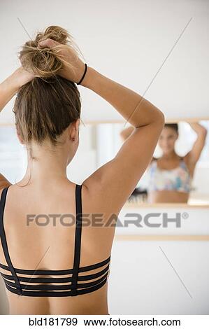 Stock Photo - Mixed race dancer tying hair in bun. Fotosearch
