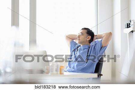 Mixed race doctor relaxing at desk View Large Photo Image Stock Photo - Mixed race doctor relaxing at desk. Fotosearch