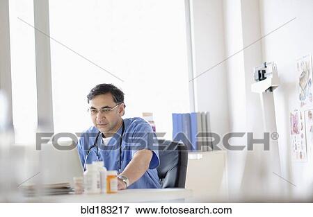 Stock Photo - Mixed race doctor working on laptop. Fotosearch