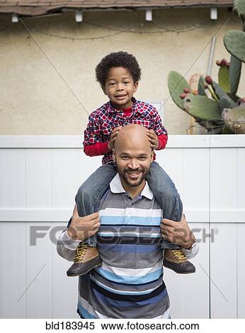 Stock Photography - Mixed race father carrying son on shoulders. Fotosearch