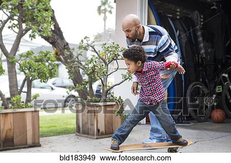 Mixed race father teaching son to ride skateboard outdoors View Large Photo Image Stock Photo - Mixed race father teaching son to ride skateboard outdoors. Fotosearch