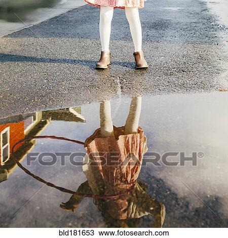 Stock Image - Mixed race girl and plastic hoop reflected in puddle. Fotosearch