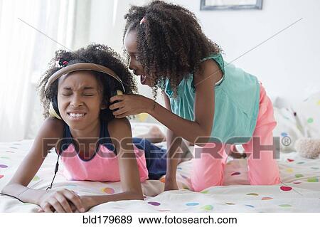 Mixed race girl bothering sister on bed View Large Photo Image Stock Photo - Mixed race girl bothering sister on bed. Fotosearch