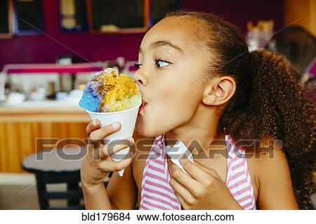 Picture - Mixed race girl eating snow cone. Fotosearch
