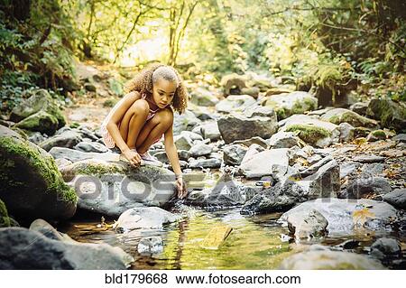 Mixed race girl exploring stream View Large Photo Image Stock Photo - Mixed race girl exploring stream. Fotosearch