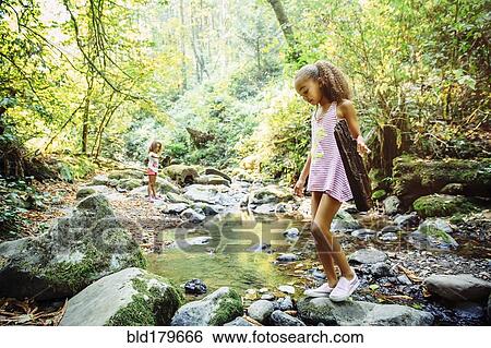 Stock Photograph - Mixed race girl exploring stream. Fotosearch
