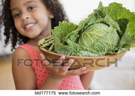 Stock Photography - Mixed race girl holding bowl of vegetables. Fotosearch