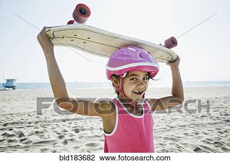 Mixed race girl holding skateboard at beach View Large Photo Image Stock Image - Mixed race girl holding skateboard at beach. Fotosearch