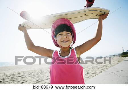 Mixed race girl holding skateboard at beach View Large Photo Image Stock Photo - Mixed race girl holding skateboard at beach. Fotosearch
