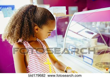Stock Image - Mixed race girl in ice cream shop. Fotosearch