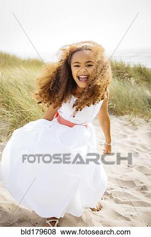 Stock Photo - Mixed race girl laughing on beach. Fotosearch