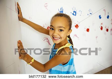 Mixed race girl making hand prints on wall View Large Photo Image Stock Image - Mixed race girl making hand prints on wall. Fotosearch