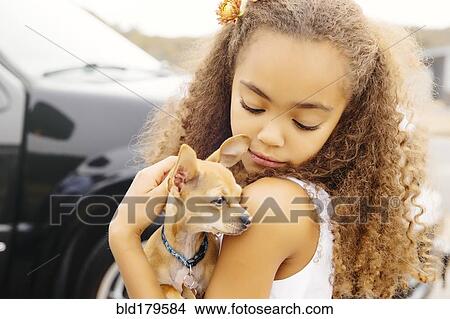 Picture - Mixed race girl petting dog outdoors. Fotosearch
