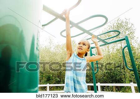 Stock Image - Mixed race girl playing on playground. Fotosearch