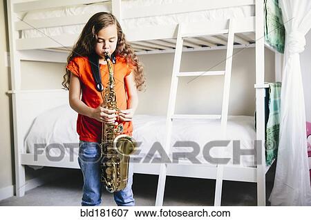 Mixed race girl playing saxophone in bedroom View Large Photo Image Stock Photo - Mixed race girl playing saxophone in bedroom. Fotosearch