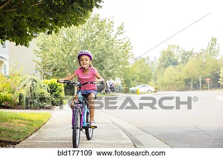 Mixed race girl riding bicycle on sidewalk View Large Photo Image Stock Photo - Mixed race girl riding bicycle on sidewalk. Fotosearch
