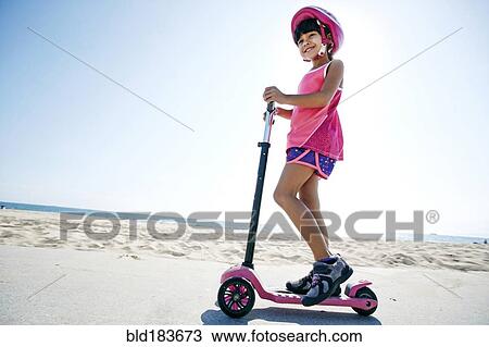 Mixed race girl riding scooter at beach View Large Photo Image Stock Image - Mixed race girl riding scooter at beach. Fotosearch