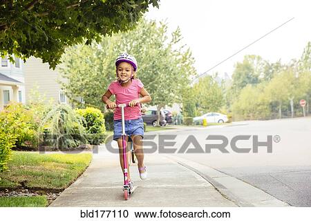 Mixed race girl riding scooter on sidewalk View Large Photo Image Stock Image - Mixed race girl riding scooter on sidewalk. Fotosearch