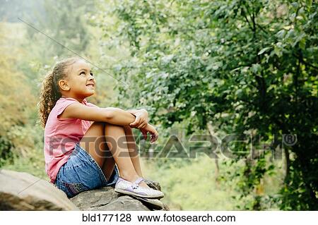 Stock Photo - Mixed race girl sitting outdoors. Fotosearch