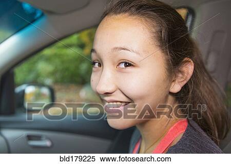Stock Photography - Mixed race girl smiling in car. Fotosearch