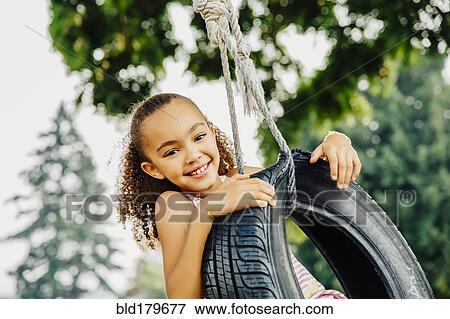 Mixed race girl smiling in tire swing View Large Photo Image Stock Photo - Mixed race girl smiling in tire swing. Fotosearch