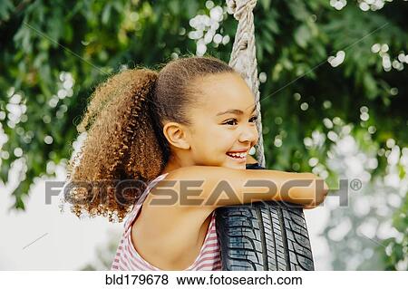 Mixed race girl smiling in tire swing View Large Photo Image Stock Photo - Mixed race girl smiling in tire swing. Fotosearch