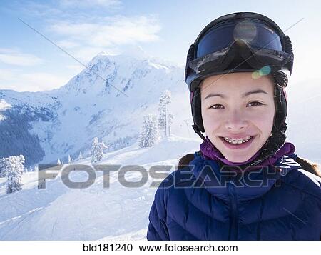 Stock Image - Mixed race girl smiling on snowy mountain. Fotosearch