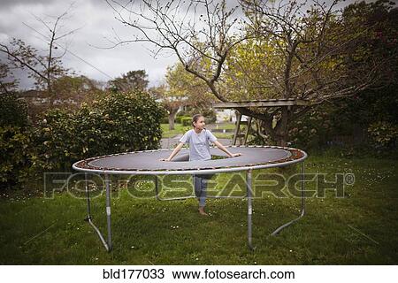 Stock Image - Mixed race girl standing in broken trampoline. Fotosearch