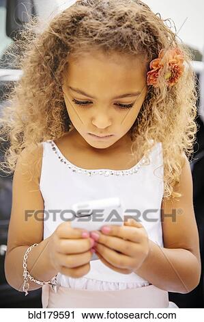 Stock Image - Mixed race girl using cell phone. Fotosearch