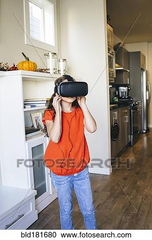 Stock Image - Mixed race girl using virtual reality goggles. Fotosearch