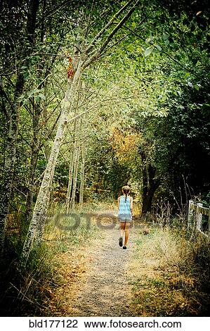 Stock Image - Mixed race girl walking on dirt path. Fotosearch