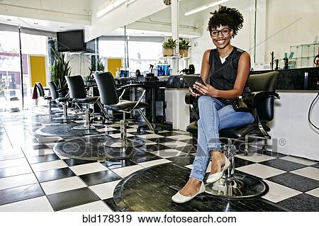 Stock Photo - Mixed race hairstylist smiling in salon. Fotosearch