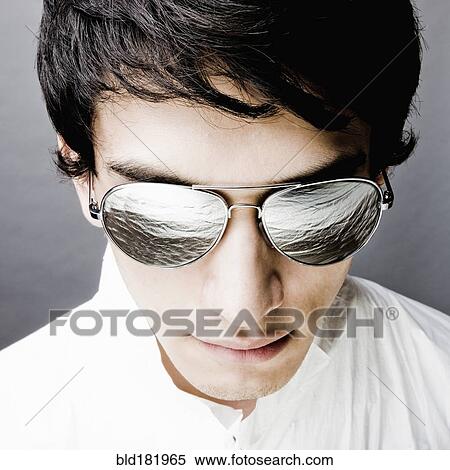 Stock Photography - Mixed race man in sunglasses reflecting water. Fotosearch