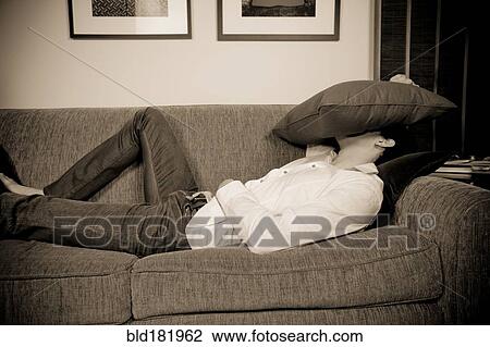 Stock Image - Mixed race man laying on sofa. Fotosearch