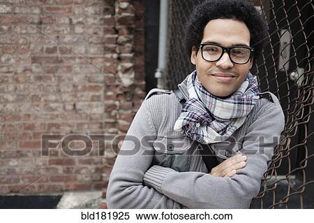 Stock Photography - Mixed race man leaning on chain link fence. Fotosearch