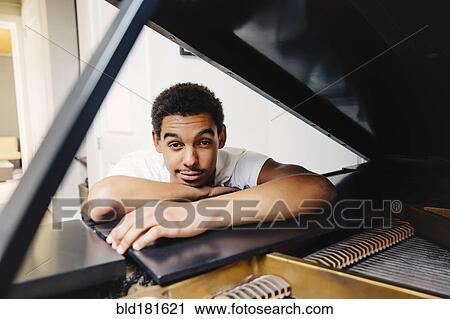 Mixed race man leaning on piano View Large Photo Image Stock Image - Mixed race man leaning on piano. Fotosearch