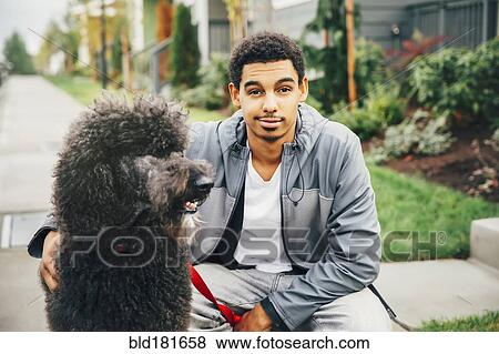 Stock Photo - Mixed race man petting dog on sidewalk. Fotosearch