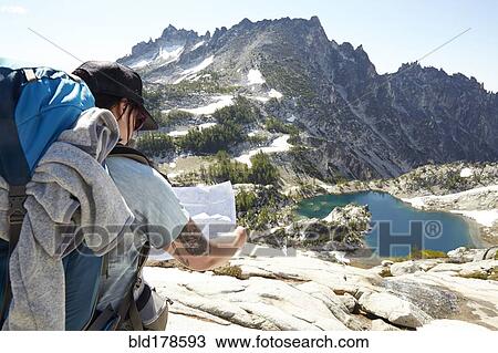 Stock Image - Mixed race man reading map on hilltop. Fotosearch