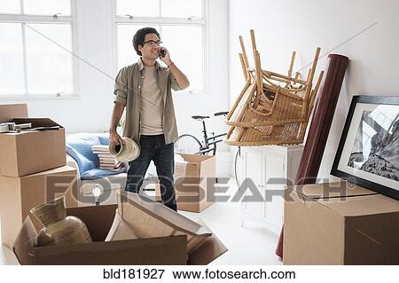 Stock Photo - Mixed race man unpacking in new home. Fotosearch