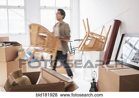 Stock Photo - Mixed race man unpacking in new home. Fotosearch