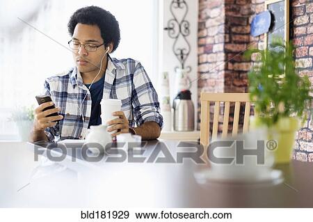 Mixed race man using cell phone in coffee shop View Large Photo Image Stock Photo - Mixed race man using cell phone in coffee shop. Fotosearch