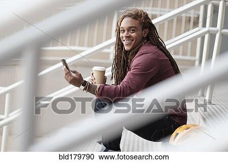 Mixed race man using cell phone on staircase View Large Photo Image Stock Image - Mixed race man using cell phone on staircase. Fotosearch