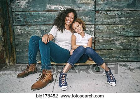 Mixed race mother and daughter sitting on skateboard View Large Photo Image Stock Image - Mixed race mother and daughter sitting on skateboard. Fotosearch
