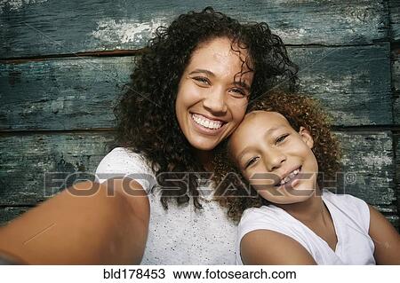 Mixed race mother and daughter taking selfie View Large Photo Image Stock Image - Mixed race mother and daughter taking selfie. Fotosearch