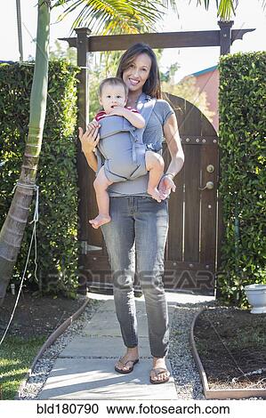 Stock Image - Mixed race mother carrying baby in sling. Fotosearch