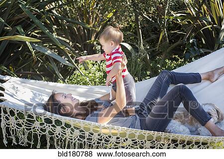 Stock Photo - Mixed race mother holding baby in hammock. Fotosearch