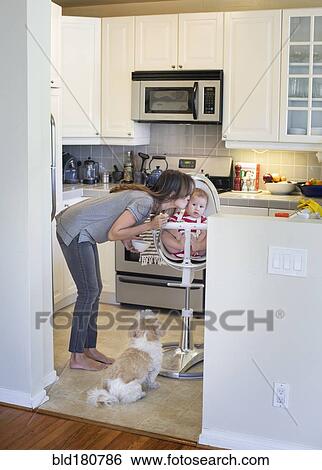 Stock Photograph - Mixed race mother kissing baby in kitchen. Fotosearch